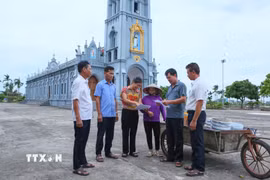 Cán bộ xóm 2, xã Nghĩa Sơn tới nhà thờ trên địa bàn để tuyên truyền, vận động người dân đồng thuận với chủ trương sắp xếp, tổ chức lại thôn, tổ dân phố. (Ảnh: Công Luật/TTXVN)