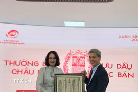 Cục trưởng Cục Văn thư và Lưu trữ nhà nước Đặng Thanh Tùng tặng bà Elena Bezdetko, Phu nhân Đại sứ Nga tại Việt Nam bản in dập từ Mộc bản về Quốc hiệu Việt Nam. (Ảnh: Chu Thanh Vân/TTXVN)