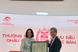 Cục trưởng Cục Văn thư và Lưu trữ nhà nước Đặng Thanh Tùng tặng bà Elena Bezdetko, Phu nhân Đại sứ Nga tại Việt Nam bản in dập từ Mộc bản về Quốc hiệu Việt Nam. (Ảnh: Chu Thanh Vân/TTXVN)