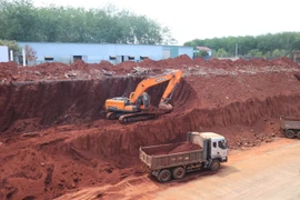 Sau khi báo chí phản ánh, chiều 2/3, một số phương tiện cơ giới đã bắt đầu hạ taluy khu vực nhà dân bị “treo cao.” (Ảnh: Đậu Tất Thành/TTXVN)