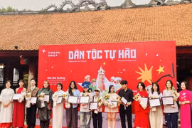 Đại diện Ban tổ chức trao chứng nhận tham gia trưng bày tranh “Dân tộc tự hào” cho các họa sỹ. (Ảnh: Tuyết Mai/TTXVN)