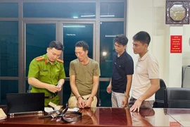Khám xét đối tượng Chảo Duần Chình tại cơ quan Công an. (Ảnh: TTXVN phát)
