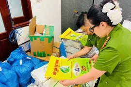 Lực lượng chức năng kiểm tra bao bì giả thương hiệu gạo ST25. (Ảnh: TTXVN)