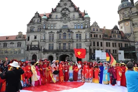 Hơn 200 chị em trong tà áo dài rực rỡ cùng lá cờ Tổ quốc tung bay giữa thành phố cổ kính Dresden (Đức). (Ảnh: Phương Hoa/TTXVN)