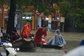 Nhiều người chọn đi bằng thuyền để đi qua các đoạn đường ngập sâu. (Ảnh: Văn Dũng/TTXVN)