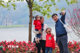 Cả gia đình cùng nhau ghi lại khoảnh khắc của mùa Xuân bên hồ Gươm. (Ảnh: Thanh Tùng/TTXVN)