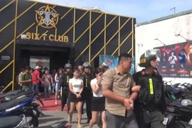 Công an đưa các đối tượng trong quán bar Six T Club về trụ sở. (Ảnh: Công an cung cấp.)