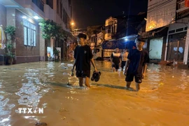 Người dân chủ động di dời khi nước sông dâng vào đường Thanh Niên. (Ảnh: Đinh Thùy/TTXVN)