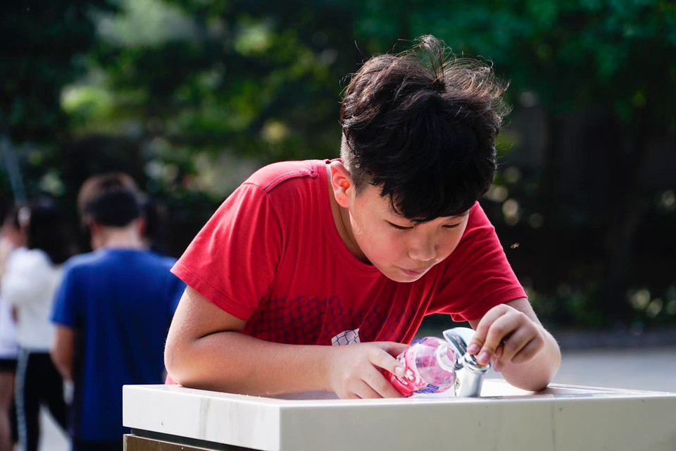 Một bạn nam đến lấy nước tiếp sức sau khi hoạt động thể thao. (Ảnh: PV/Vietnam+)