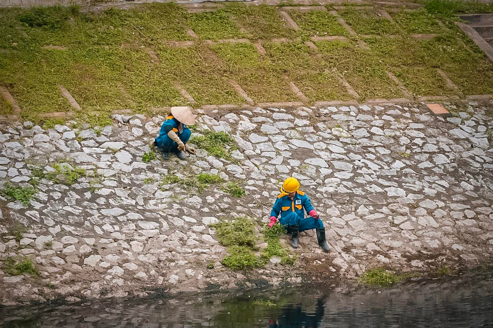 Ngoài việc dọn rác dưới sông thì những người nhân viên này còn dọn dẹp, cắt tỉa làm đẹp cho cảnh quan ven sông. (Ảnh: PV/Vietnam+)
