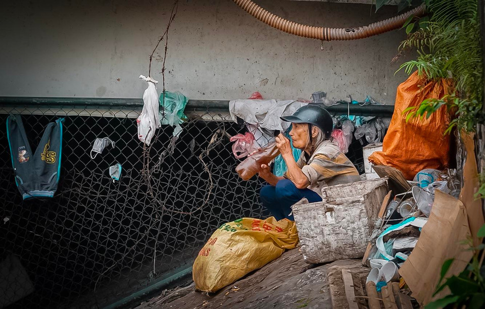 Cụ già nghỉ trưa sau khi thu gom chai lọ ven sông để kiếm sống. Đây cũng là một nguồn thu nhập của người nghèo. (Ảnh: PV/Vietnam+)