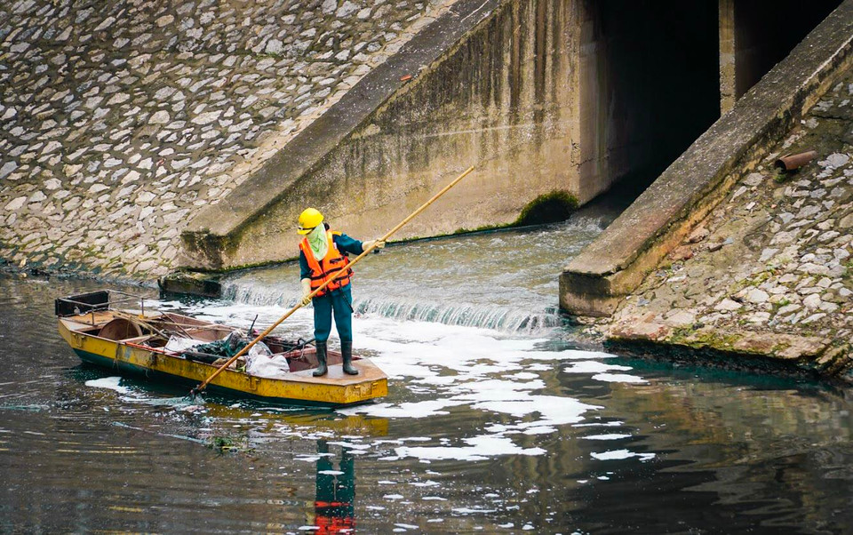 Những người công nhân này ngày ngày đứng trên thuyền và dọn rác thải trên sông bằng cây đinh ba của mình. (Ảnh: PV/Vietnam+)