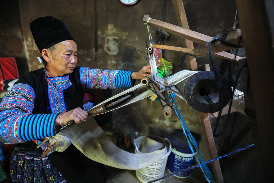 Một người phụ nữ Mông ở xã Pà Cò miệt mài bên khung cửi để dệt ra những tấm vải thổ cẩm Mông bền đẹp. (Ảnh: Trọng Đạt/TTXVN)