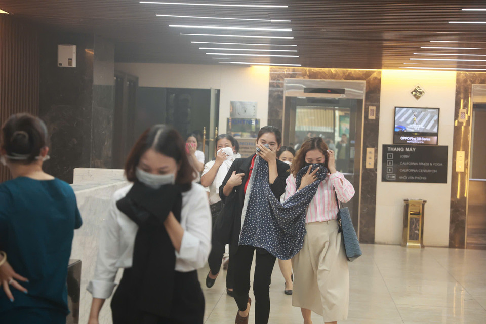 Khói lan mù mịt sang toà Capital Tower, người dân đang phải thoát nạn ra ngoài. (Ảnh: Hoài Nam/Vietnam+)