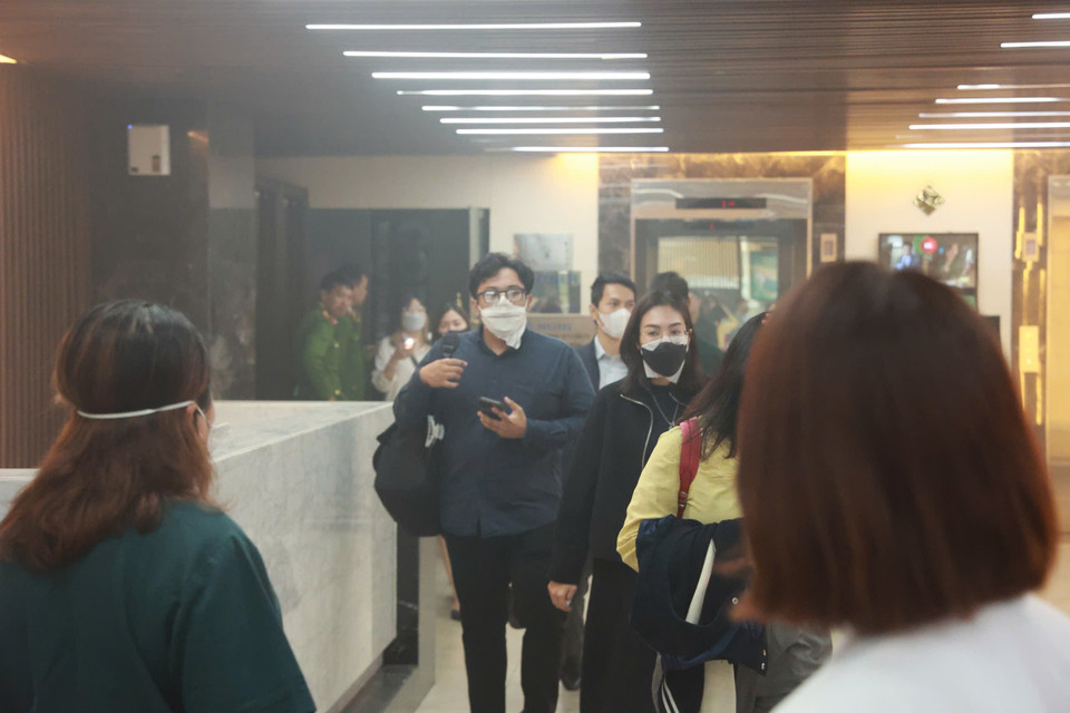 Khói lan mù mịt sang toà Capital Tower, người dân đang phải thoát nạn ra ngoài. (Ảnh: Hoài Nam/Vietnam+)