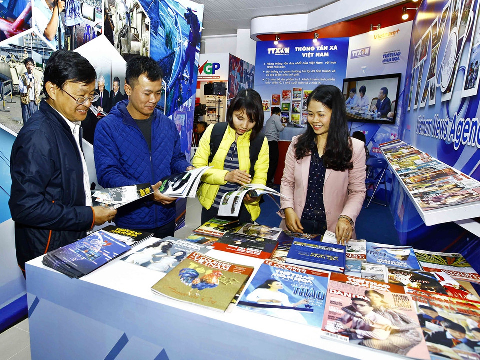 Khách quan hào hứng tìm hiểu kỹ các ấn phẩm tại gian hàng của Thông tấn xã Việt Nam. (Ảnh: Doãn Tấn/TTXVN)