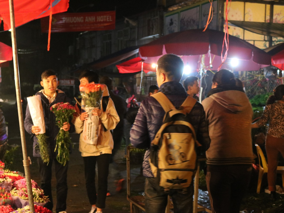 Các bạn nam sinh viên hào hứng đi mua hoa từ sáng sớm. (Ảnh: Nam Giang/Vietnam+)