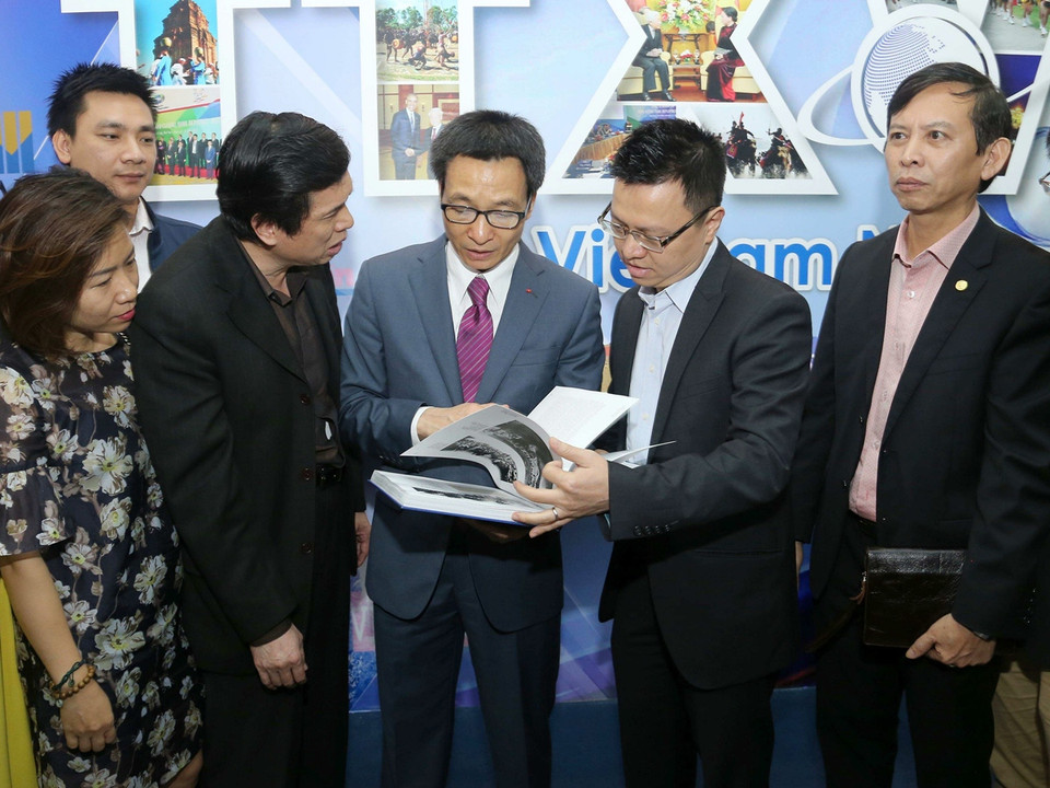 Phó Thủ tướng Vũ Đức Đam xem những trang sách ghi lại những chặng đường phát triển của Thông tấn xã Việt Nam. (Ảnh: Doãn Tấn/TTXVN)