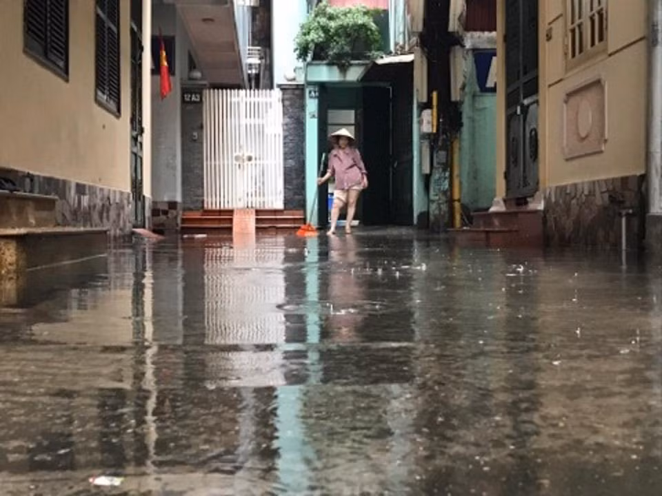Nhiều người dân đang quét nước từ trong các con ngõ. (Ảnh: PV/Vietnam+)