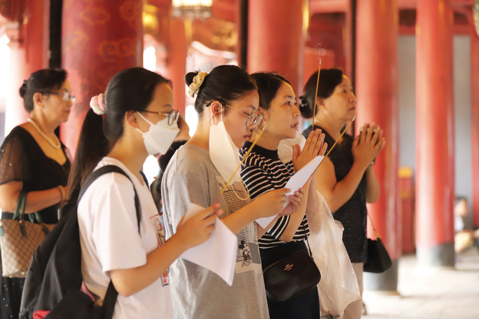 Chị Phạm Thị Hồng Hạnh (Hà Nội) hôm nay dẫn con gái và cháu đến dâng hương. Chị chia sẻ: ‘Giống như tâm trạng hồi hộp của các phụ huynh khác, hôm nay tôi dẫn các con đến Văn Miếu mong cầu các con có tâm thế ổn định nhất trong kỳ thi vào cuối tuần này.’ (Ảnh: Hoài Nam/Vietnam+)