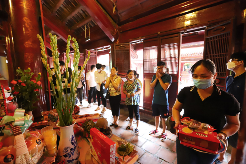 Ngoài việc nhắc nhở con em ôn luyện thật kỹ, các bậc phụ huynh còn củng cố niềm tin cho con em bằng việc đến dâng hương ở Trường đại học đầu tiên của Việt Nam. (Ảnh: Hoài Nam/Vietnam+)