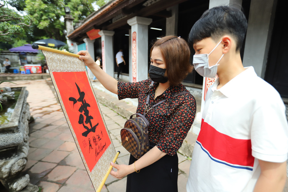 Chị Thủy hôm nay xin chữ cho con trai mình, mong cho con mình sẽ có kết quả thuận lợi cũng như củng cố niềm tin cho con trai. (Ảnh: Hoài Nam/Vietnam+)