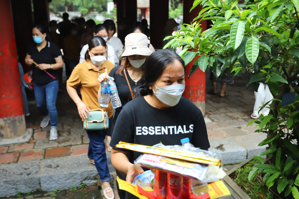 Phụ huynh đi cầu may cho con cái dâng hương, lễ vật hoa quả và sớ. (Ảnh: Hoài Nam/Vietnam+)