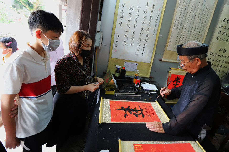 Sau khi lễ xong, các sỹ tử được phụ huynh đưa đi xin chữ thư pháp cầu mong may mắn, đỗ đạt. (Ảnh: Hoài Nam/Vietnam+)