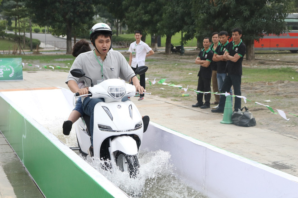 Khách hàng thăm quan đang vận hành bài thử nghiệm chống ngập nước. Mẫu xe điện này có chỉ số chống nước chuẩn IP67. (Ảnh: Minh Hiếu/Vietnam+)