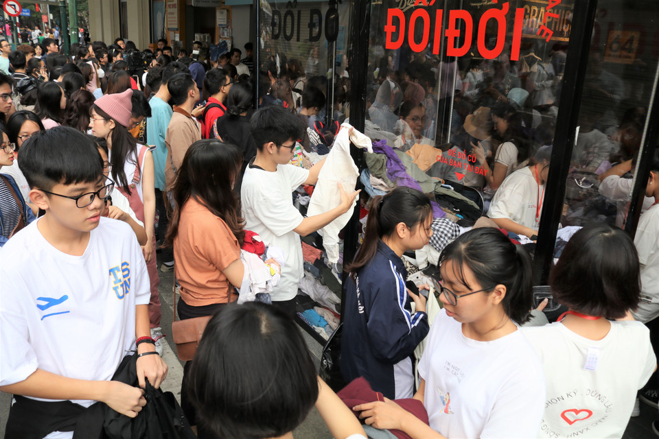 Cầm trên tay túi quần áo cũ chuẩn bị trước ở nhà, nhiều bạn trẻ xếp hàng cùng bạn bè chờ đến lượt gửi đồ cũ tại quầy. (Ảnh: Minh Hiếu/Vietnam+)