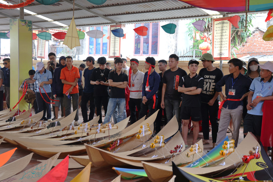 Hội thi năm nay có hơn 60 người tham dự, không chỉ là dân làng Bá Giang mà còn từ cả các làng khác như Hạ Mỗ, Tân Hội, Liên Trung... Người tham gia thi mang diều tới xếp thành hàng trước cửa miếu để "trình diều" trước các thánh nhân. (Ảnh: Hồng Ngọc/Vietnam+)