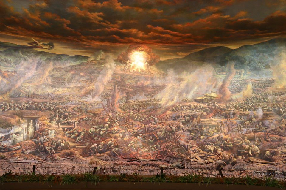 Trường đoạn 3 “Cuộc đối đầu lịch sử”: với những hình ảnh hầm hào, dây thép gai, trận đánh giáp lá cà… phản ánh sự khốc liệt của chiến trường. Kết thúc trường đoạn bằng hình ảnh cột khói từ quả bộc phá trong lòng đồi A1. (Ảnh: Vietnam+)