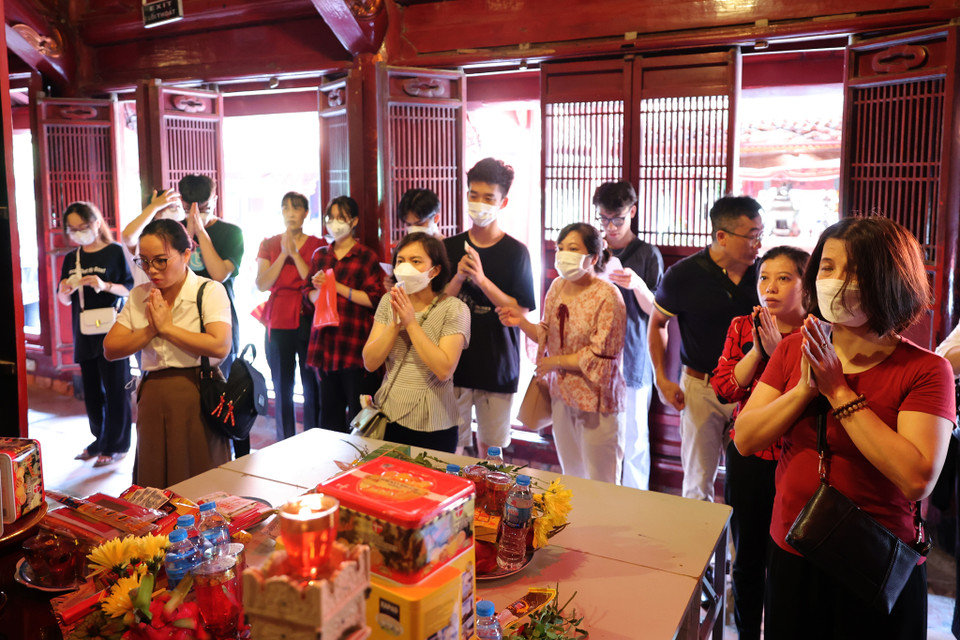 Từng nhóm phụ huynh và học sinh thành kính dâng hương và lễ vật, cầu mong cho thí sinh vượt vũ môn thành công. (Ảnh: Hoài Nam/Vietnam+)