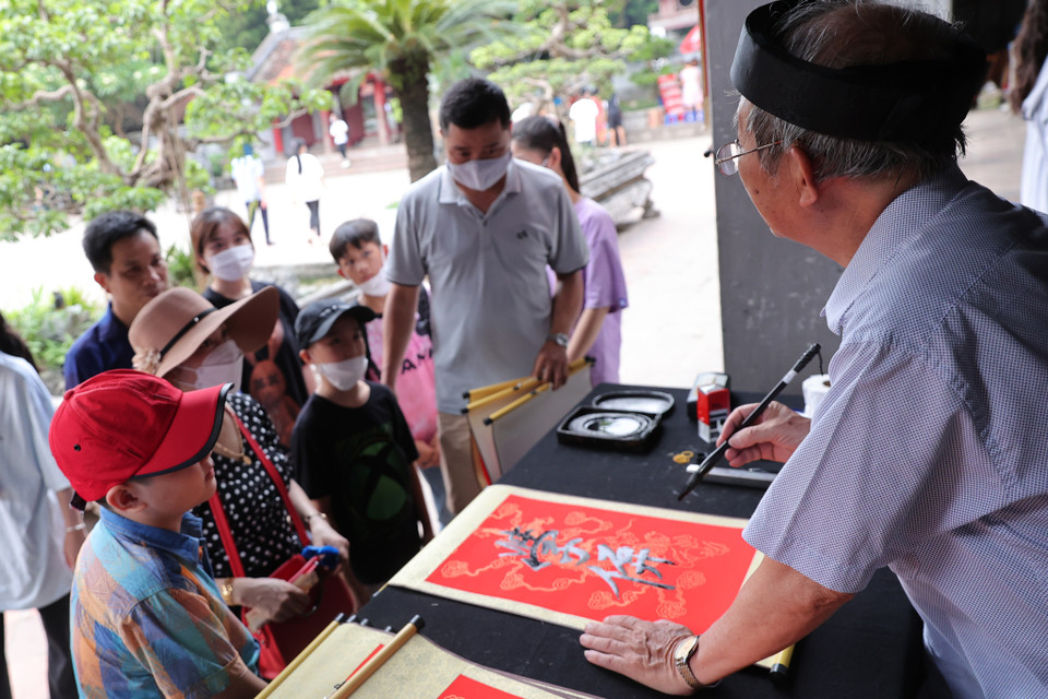 Sau khi dâng hương và lễ vật, các sỹ tử được phụ huynh đưa đi xin chữ cầu may mắn, đỗ đạt. (Ảnh: Hoài Nam/Vietnam+)