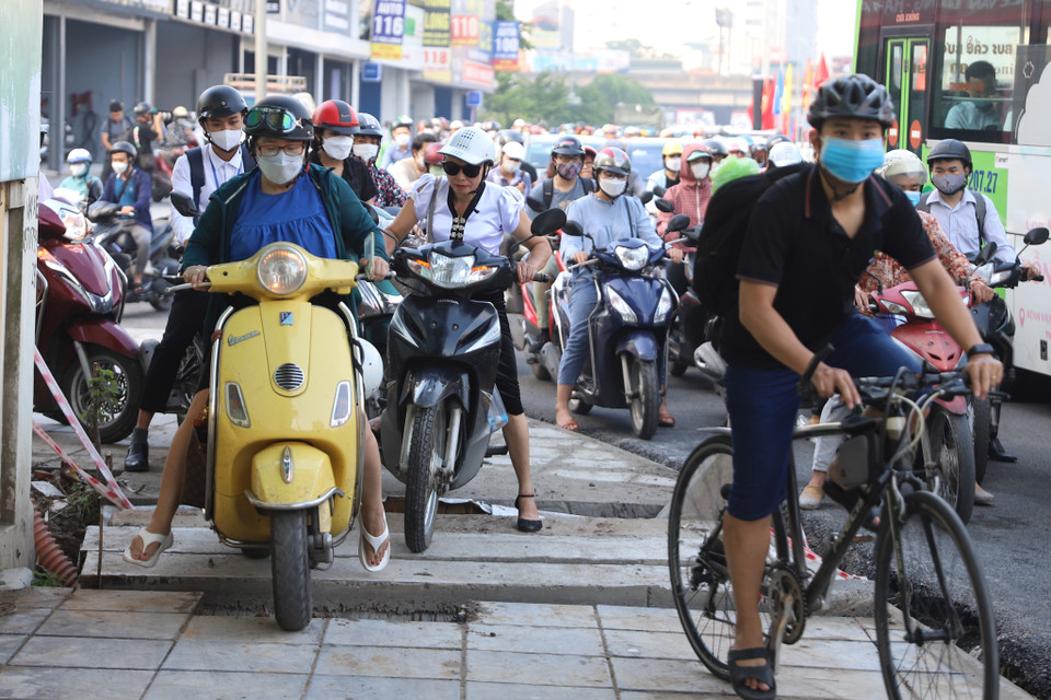 Nhiều xe máy lựa chọn cho mình lối đi của người đi bộ để nhanh chóng thoát khỏi cảnh ùn tắc, kịp giờ làm. (Ảnh: Hoài Nam/Vietnam+)
