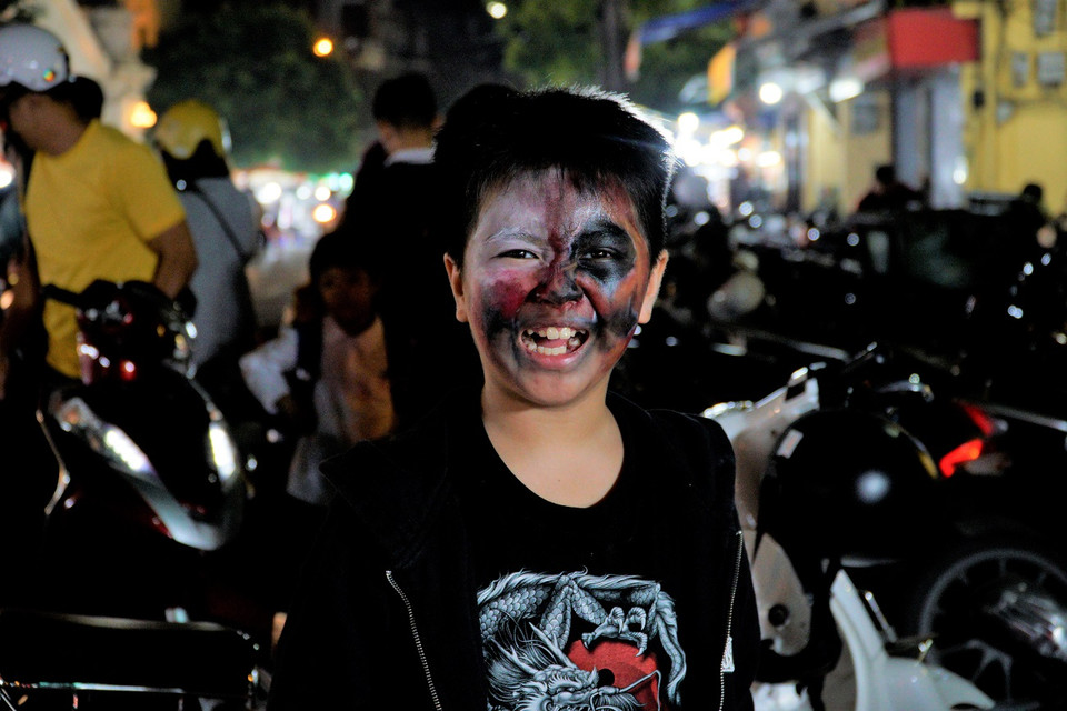 Một bé trai đang khoe chiếc mặt nạ “tự làm” của mình. (Ảnh: Minh Hiếu/Vietnam+)