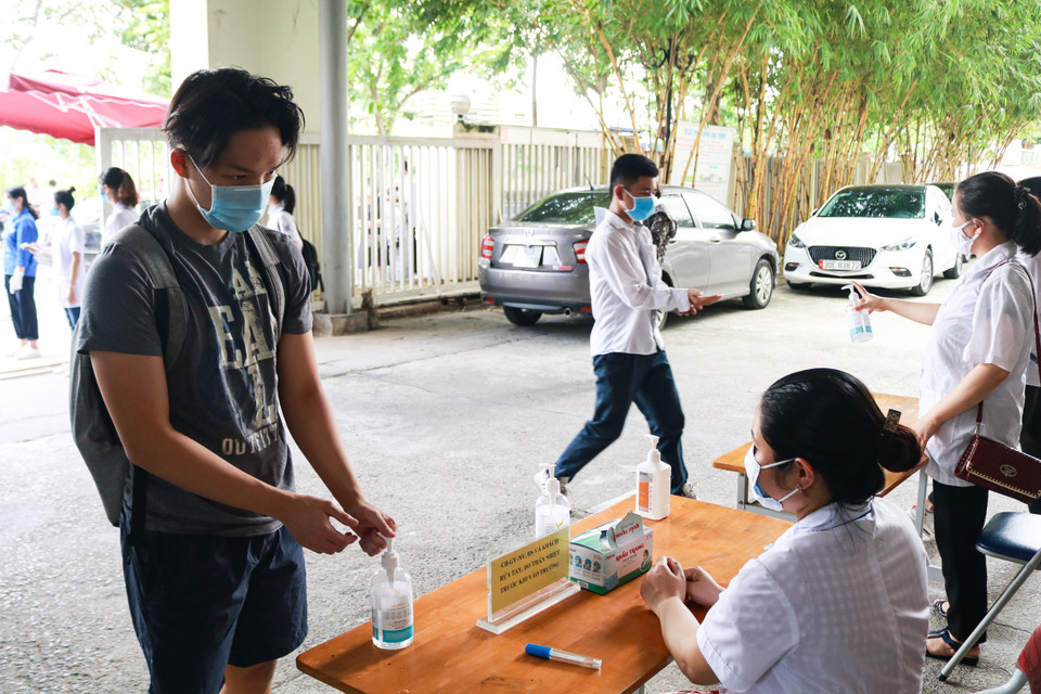 Sau đó, thí sinh phải rửa tay bằng nước sát khuẩn, đững giãn cách trước khi vào phòng dự thi. (Ảnh: Nguyên An/Vietnam+)