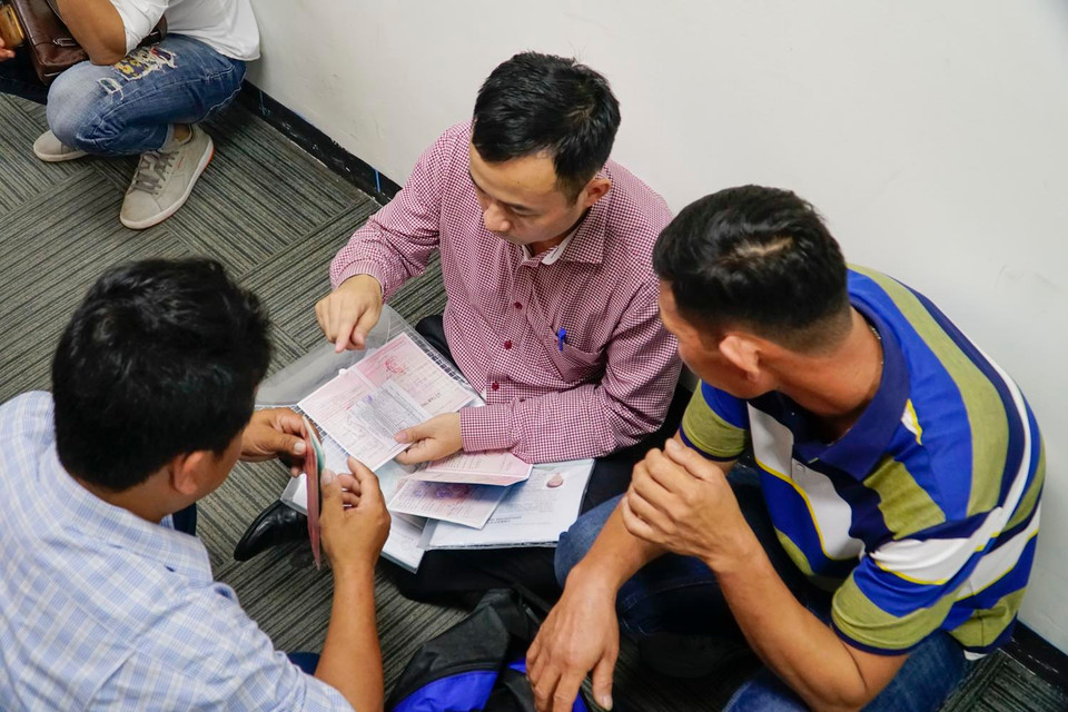 Hình ảnh nhóm người đang ngồi sắp xếp giấy tờ thủ tục để xin visa. (Ảnh: PV/Vietnam+)