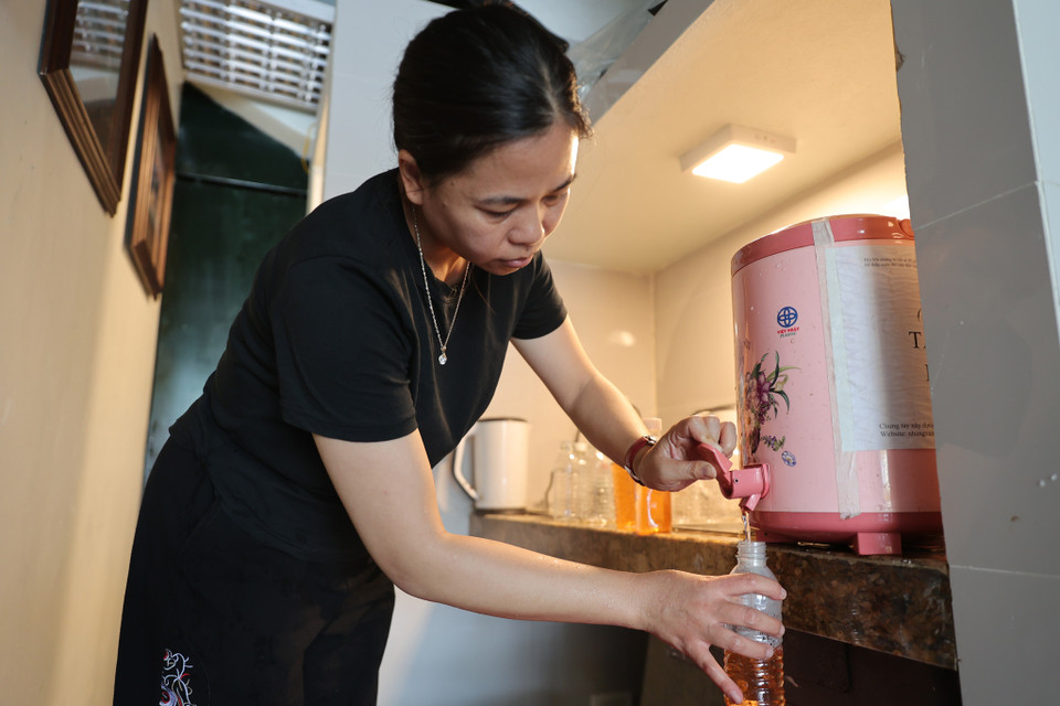 Ngoài nước lọc đóng chai sẵn chị Hương còn đun nước trà từ sớm, để nguội sau đó đóng vào chai phát cho người dân. (Ảnh: Hoài Nam/Vietnam+)