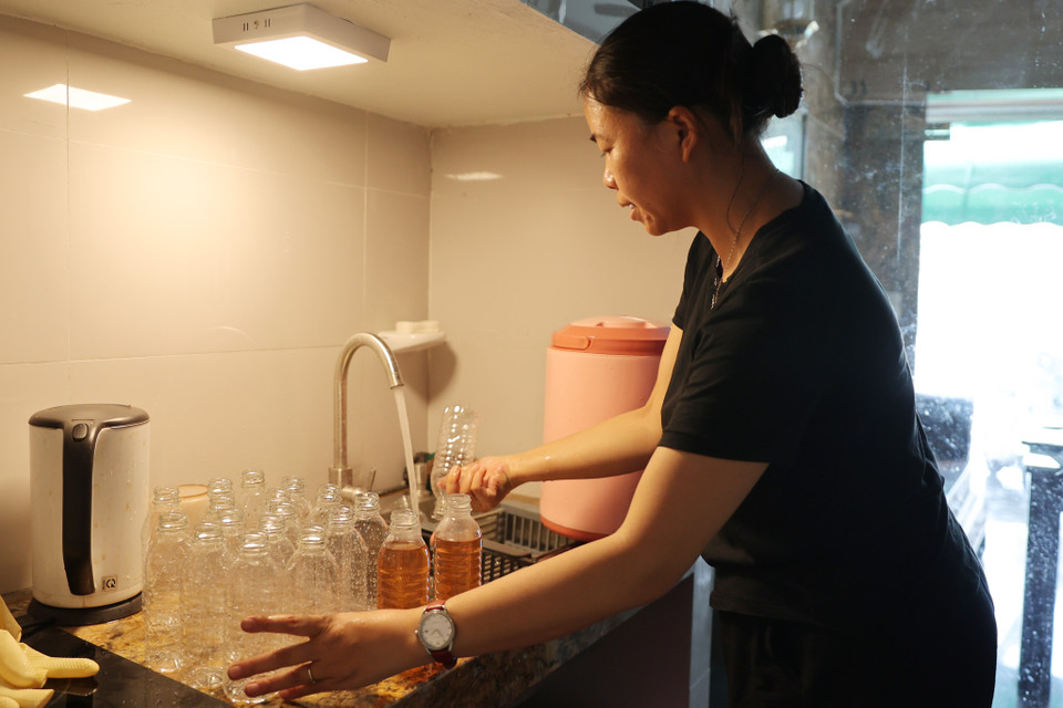 Vợ anh hằng ngày ra chợ mua chai nhựa và rửa sạch sẽ trước khi đóng nước vào chai. Chị Hương chia sẻ: 'Mình làm miễn phí nhưng phải làm cẩn thận, mang cái tâm của mình trong đó.' (Ảnh: Hoài Nam/Vietnam+)