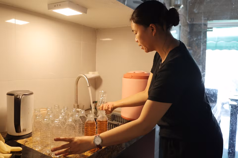 Vợ anh hằng ngày ra chợ mua chai nhựa và rửa sạch sẽ trước khi đóng nước vào chai. Chị Hương chia sẻ: 'Mình làm miễn phí nhưng phải làm cẩn thận, mang cái tâm của mình trong đó.' (Ảnh: Hoài Nam/Vietnam+)