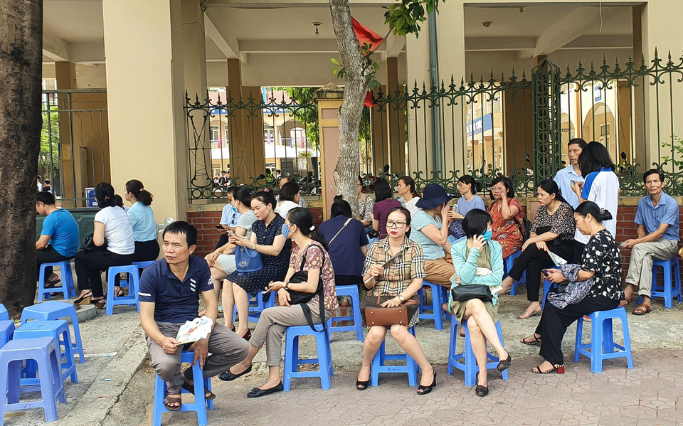 Phụ huynh ngồi ngoài đợi thí sinh làm thủ tục thi. Sáng mai, họ sẽ còn lo lắng và hồi hợp hơn khi các con bước vào ngày thi chính thức với môn ngữ văn. (Ảnh: Nguyên An/Vietnam+)