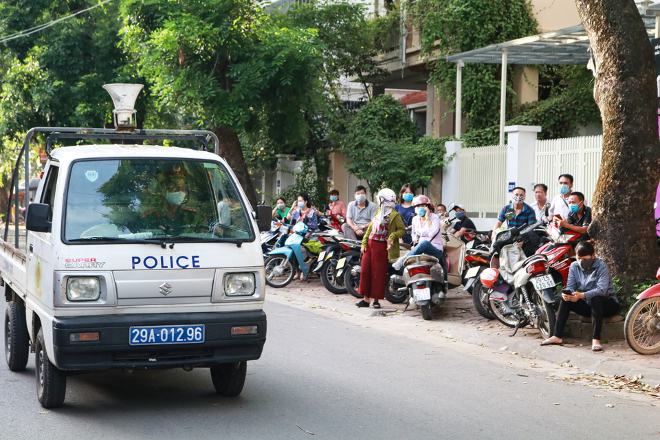  Không chỉ thí sinh, phụ huynh đợi bên ngoài cổng trường cũng được yêu cầu thực hiện nghiêm chỉnh công tác phòng chống dịch. Mọi người liên tục được lực lượng cảnh sát nhắc nhở đeo khẩu trang và đứng giãn cách. (Ảnh: Nguyên An/Vietnam+)
