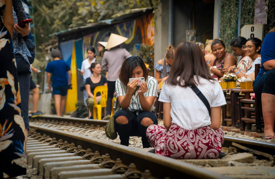 Việc ngồi ăn uống, check in chụp ảnh giữa đường ray thế này rất nguy hiểm. Tuy nhiên với một số người đó lại là một trải nghiệm. (Ảnh: Minh Hiếu/Vietnam+)