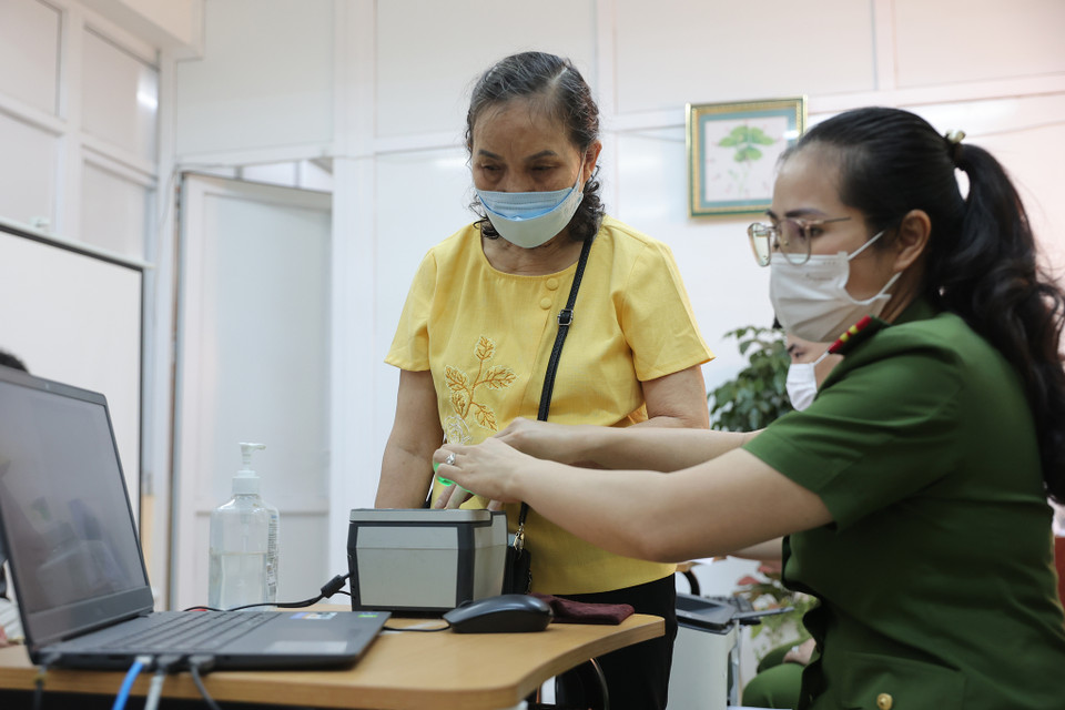 Công an quận Thanh Xuân đã chỉ đạo các phường tận dụng các kênh truyền thông để giúp người dân tiếp cận được thông tin. Bà Bùi Thị Hồng 74 tuổi sống tại phường Nhân Chính nhận được thông tin qua tin nhắn nhóm Zalo của phường, ngay hôm sau bà đã ra công an quận Thanh Xuân để làm hồ sơ. (Ảnh: Hoài Nam/Vietnam+)