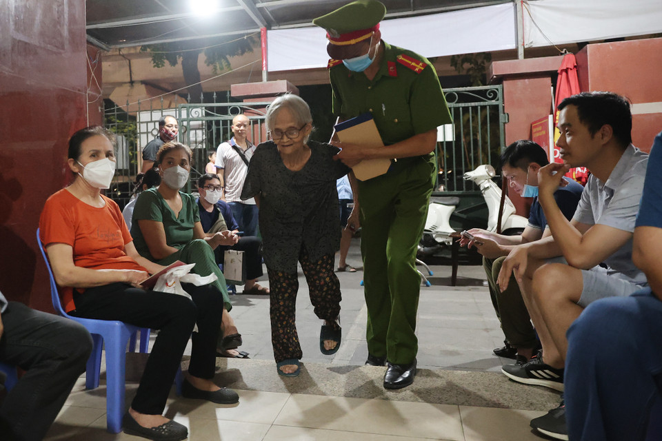 Cảnh sát khu vực đã tới tận nhà bà Phạm Thị Tám-86 tuổi (Thanh Xuân, Hà Nội) đón bà ra trụ sở làm hồ sơ. Đối với các trường hợp ốm đau không thể tới trụ sở, cảnh sát khu vực sẽ lập danh sách để công an quận tổ chức các điểm lưu động tới từng nhà. (Ảnh: Hoài Nam/Vietnam+)