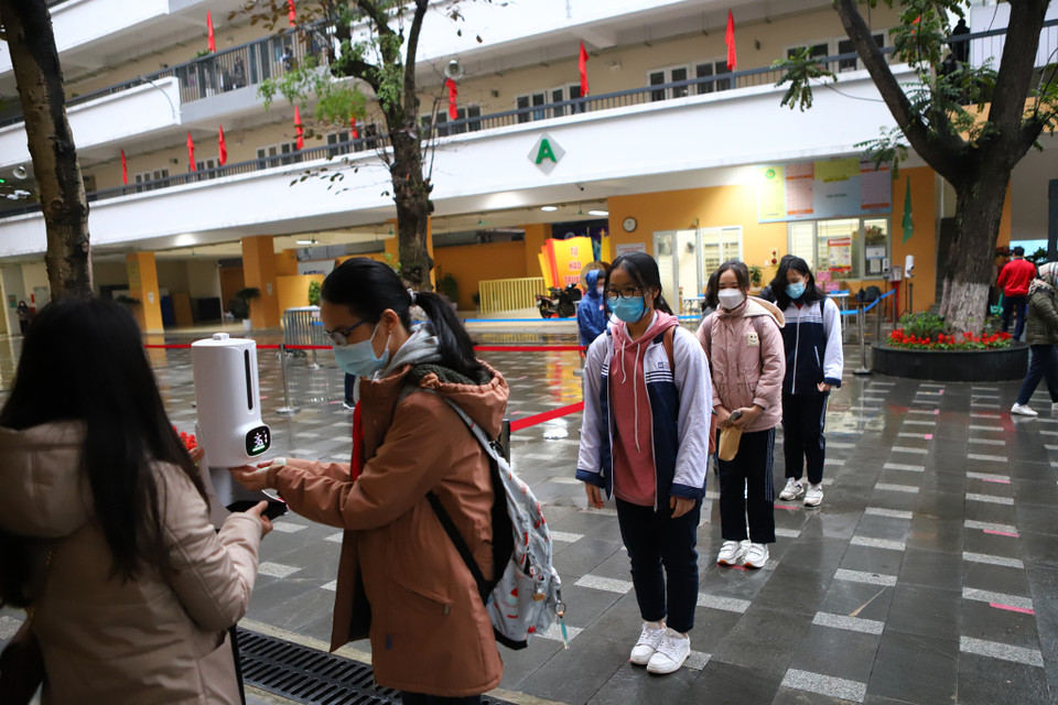 Học sinh phải đảm bảo giãn cách khi đo thân nhiệt và khử khuẩn tại khu vực cổng trường. (Ảnh: Hoài Nam/Vietnam+)