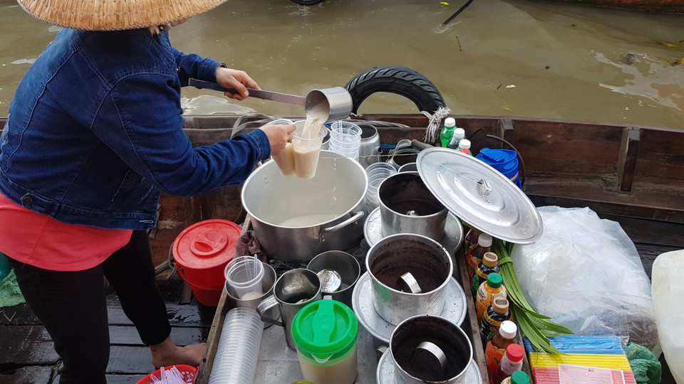 Bên cạnh bán các loại trái cây, có nhiều chiếc ghe nhỏ len lỏi khắp con sông bán điểm tâm sáng cho khách và dân địa phương như cháo, cơm sườn, hủ tiếu, bún riêu… và các loại thức uống như trà, càphê, dừa, sữa đậu nành… (Ảnh: Vietnam+)