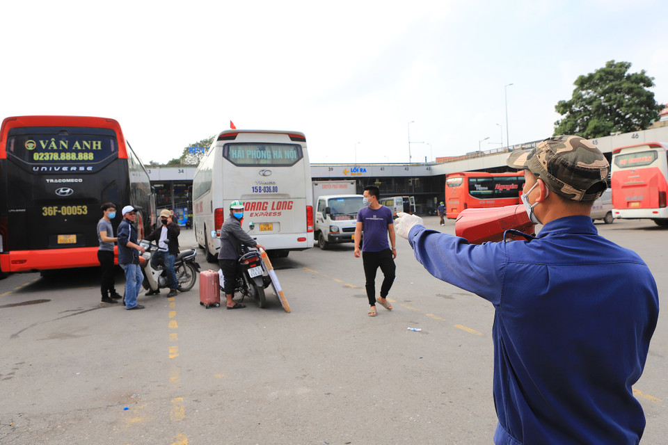 Anh Nguyễn Văn Hiếu, nhân viên bến xe Nước Ngầm luôn phải di chuyển và nhắc nhở người dân đeo khẩu trang trong khu vực bãi xe. (Ảnh: Hoài Nam/Vietnam+)