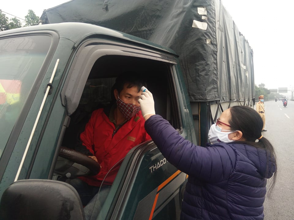 Tại các chốt, cảnh sát giao thông dừng các phương tiện, tiếp đó, lực lượng thanh tra giao thông và cảnh sát cơ động hướng dẫn các phương tiện đỗ theo hàng để các nhân viên y tế đo thân nhiệt. (Ảnh: PV/Vietnam+)